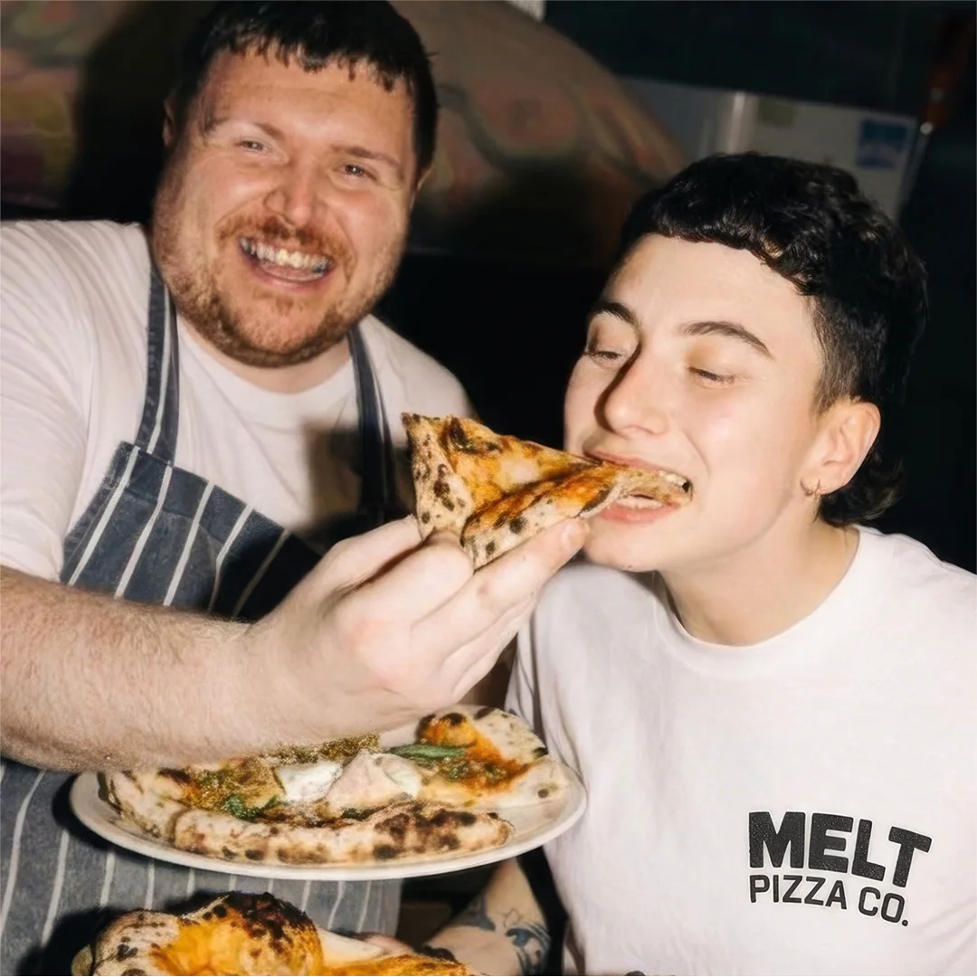 Customers sharing a pizza in Melt Pizza Co branded t-shirts