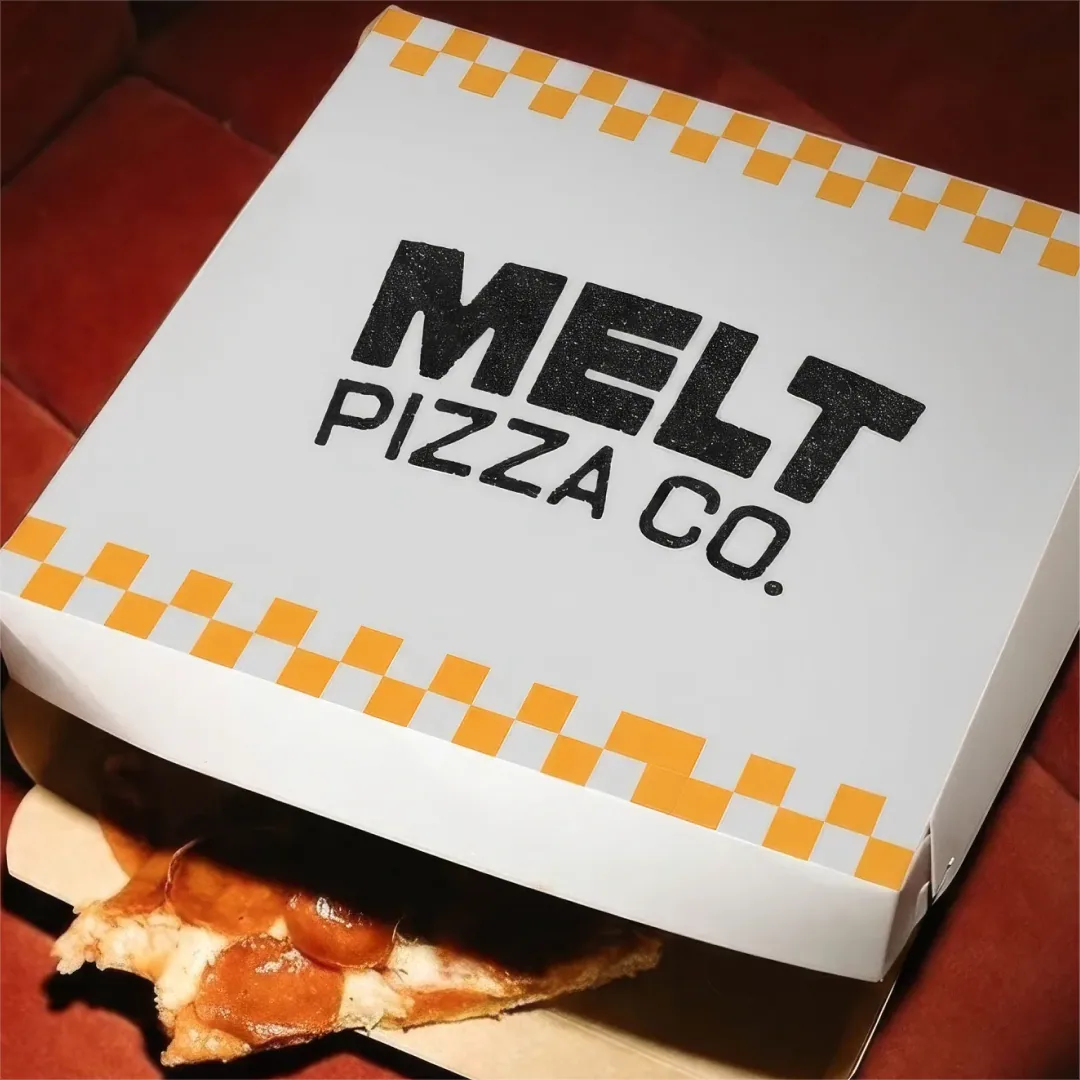 Open Melt Pizza Co box with checkerboard trim revealing a pizza slice