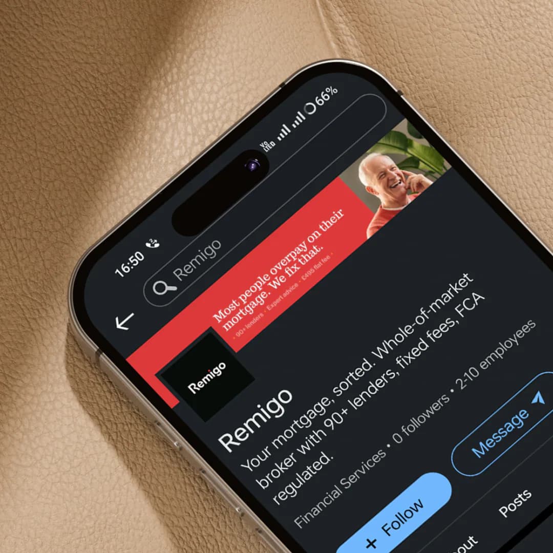 Remigo LinkedIn company profile on a phone against tan leather